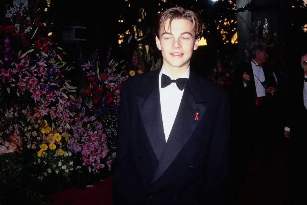 Leonardo DiCaprio, giovane e sorridente, con smoking e fiocco, pronto a ricevere i premi vinti.