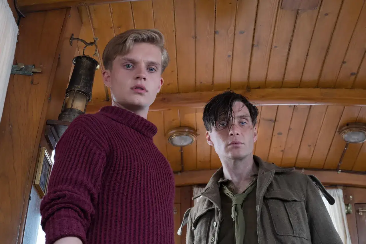 Il cast di Dunkirk: due giovani soldati, uno con un maglione bordeaux, l'altro con un'uniforme militare, guardano intensamente verso l'obiettivo.