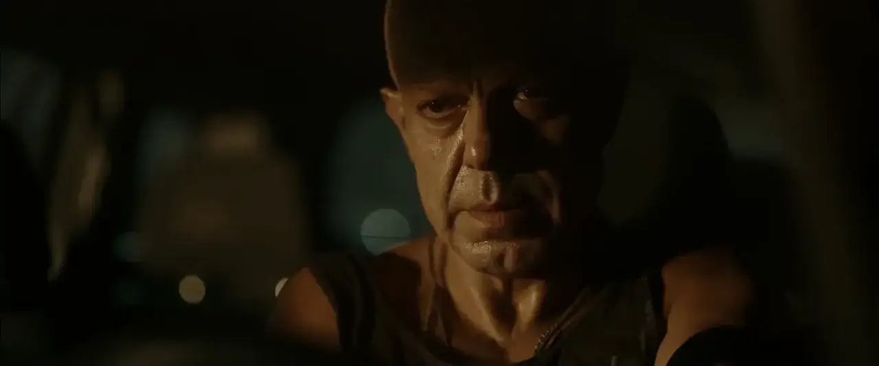 Un uomo calvo e sudato guida di notte. Il cast di Adagio (film) è intenso.