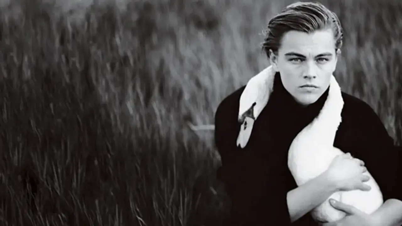 Leonardo DiCaprio abbraccia un cigno in un campo d'erba alta, in un ritratto iconico di Annie Leibovitz.