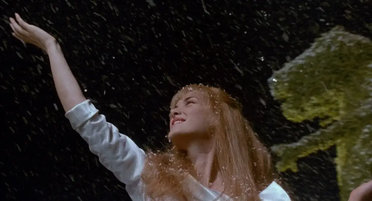 Kim, con la mano alzata, guarda la neve cadere, un dono di Edward mani di forbice.