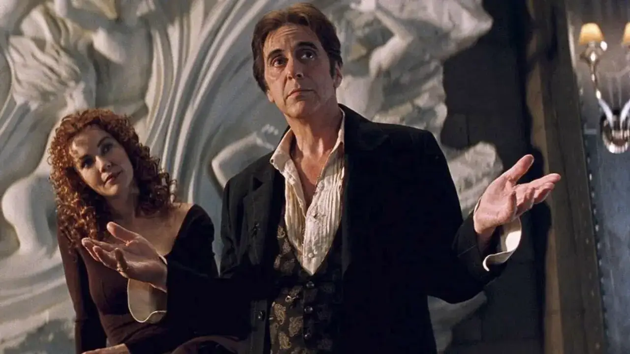 Al Pacino in un film italiano, con le mani aperte, sembra recitare uno dei suoi famosi monologhi. Accanto a lui, una donna con capelli rossi ricci.