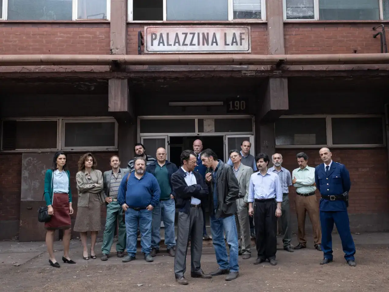 Gruppo di persone davanti alla Palazzina LAF. Le recensioni sul film sono positive.