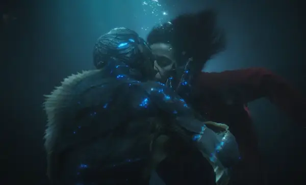 La forma dell'acqua recensione: un bacio subacqueo tra una donna e una creatura anfibia, illuminati da luci blu bioluminescenti.